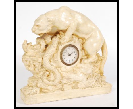 An early 20th century chalk ware mantel clock in the form of a tiger fighting a snake with central barrel clock with white en
