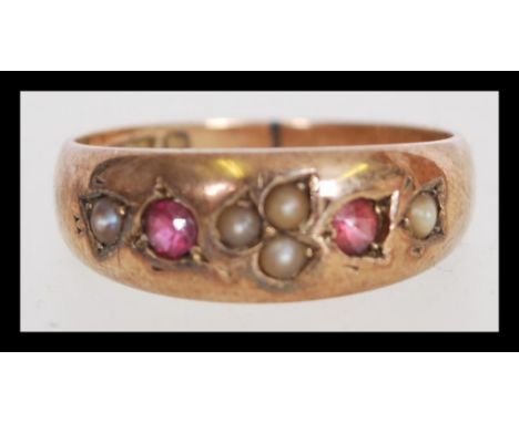 A 19th century Victorian 9ct gold ring with seed pearl inlay and two in set red stones. The item weight is 3.1 grams.