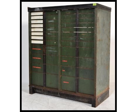 A vintage early 20th century Edwardian industrial metal filing cabinet having a graduating set of drawers with green enamel p