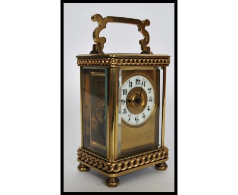 A 20th century gilt brass carriage clock raised on bun feet with curb link chain decoration. The white enamel chapter ring ha
