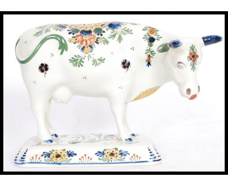 A 19th / 20th Century Delft ceramic figurine of a cow having hand painted floral sprays with painted horns. Painted marks to 