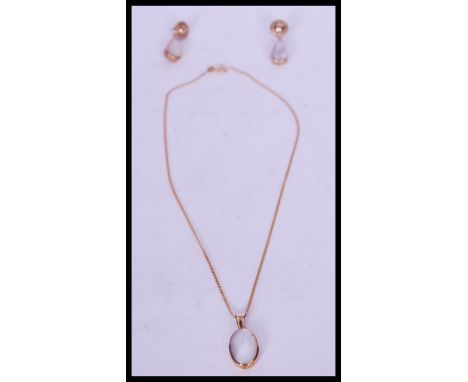 A pair of contemporary 9ct gold stud drop earrings with pearlescent inlay with a matching 9ct gold oval pendant necklace on a