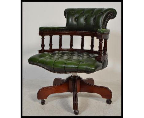 A 20th century green Leather Chesterfield Captains deep button back mahogany framed swivel office / desk chair having a spind