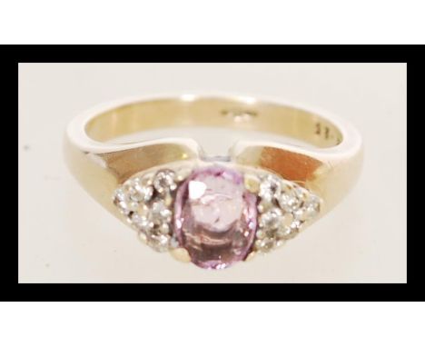 A hallmarked 9ct gold pink sapphire and diamond ring having a central pink sapphire with diamond set shoulders. Approx 25 poi