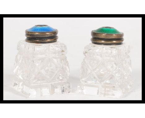 A pair of early 20th century small cut glass jars on square bases with stamped sterling silver 925 lids having pierced detail