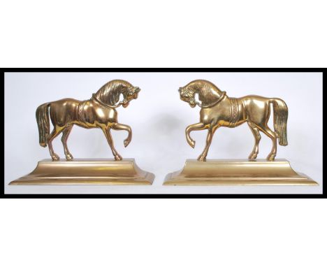 A pair of 19th century brass andiron firedog fireside ornaments in the form of horses being raised on plinth bases.&nbsp;Meas