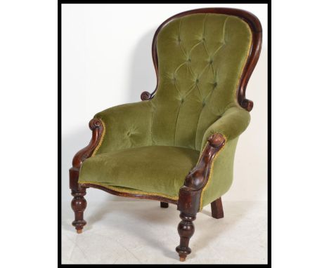 A 19th Century Victorian mahogany armchair with carved scrolling frame, raised on turned supports, button back velour upholst