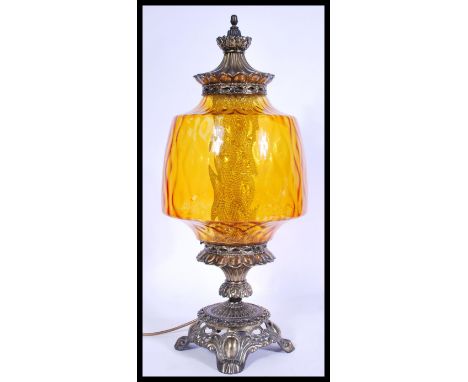 A vintage 20th century table lamp in the form of an antique oil lamp having an amber glass reservoir with brass scrolled base