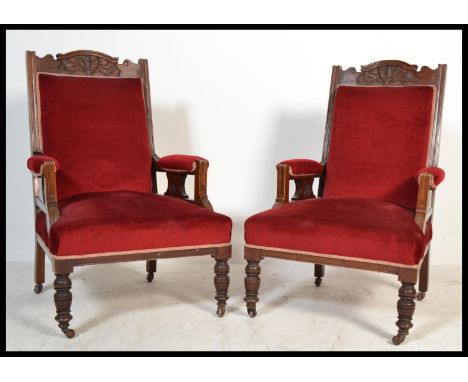 A pair of early 20th Century Edwardian button back upholstered library armchairs having red velour over stuffed seat pads rai