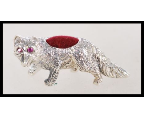 A vintage 20th century silver pin cushion model as a fox with ruby eyes and a red cushion to the back.