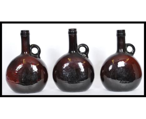 A set of three 19th century Dutch amber glass wine flask bottles having moon flask shaped bodies with single loop handles to 