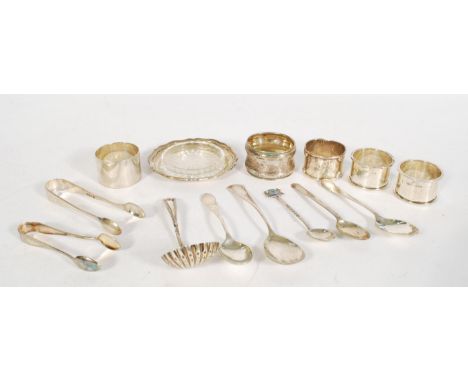 A collection of small silver wares to include a caddy spoon of shell form, a pair of sugar tongs, a selection of silver teasp