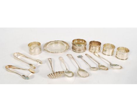 A collection of small silver wares to include a caddy spoon of shell form, a pair of sugar tongs, a selection of silver teasp