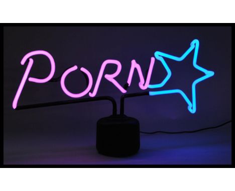 A contemporary retro style novelty neon sign table lamp raised on a circular base reading porn star in pink and blue.&nbsp;Me