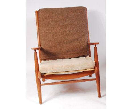 A 1960s teak framed open armchair, having cushion upholstery and sprung seat, labelled 'Scandart Ltd High Wycombe Bucks' vers