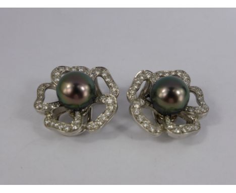 A Pair of Platinum and Tahitian Pearl Clip Earrings. The floral design earrings set with  2 x 10 mm pearls with approx 1.35 c