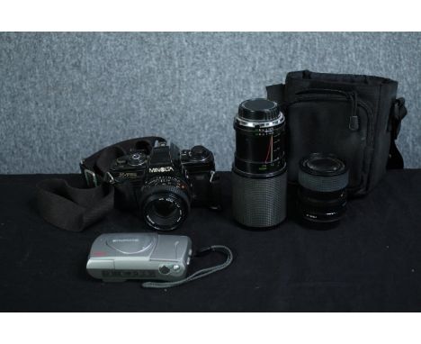 A Minolta X-700 35mm camera with three lenses and camera bag along with an Olympus camera. H.17cm. (largest) 