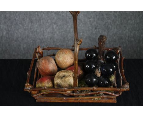 A Victorian Hazelwood basket with a collection of hand painted ceramic fruit and a bunch of glass grapes. H.26 W.28 D.20cm. 