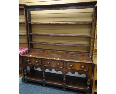 A Victorian oak Welsh dresser having a planked platform base, three drawers and an open rack with six spice drawers and three