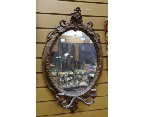 An antique gilt framed oval wall mirror with candle sconce base, 73cms high Condition reports provided on request by email fo