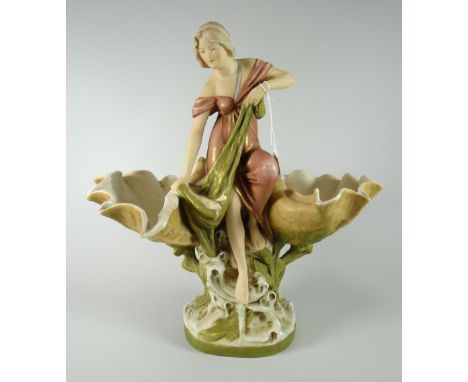 A Royal Dux pottery model of a maiden catching a fish in a net, flanked by two open clam shells over a naturalistic oval base