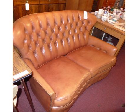 A Chesterfield style two seater sofa upholstered in buttoned tan leather with brass studded detail