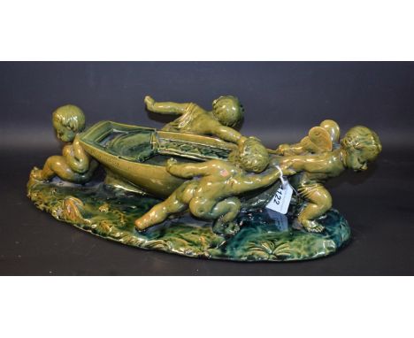 A Victorian Art Pottery terracotta table centre, modelled as a winged cherub and three companion putti manoeuvring a rowing b