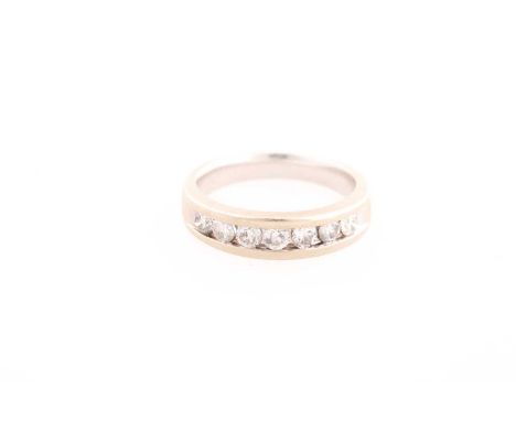 A seven stone half hoop diamond ring, the round brilliant cut diamond channel set to a white metal band stamped '14k'. 7.3 gr