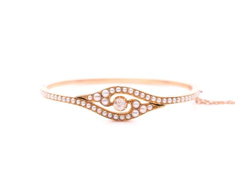 A late 19th / early 20th century yellow gold, diamond, and seed pearl bangle, the bracelet centred with an old round-cut diam