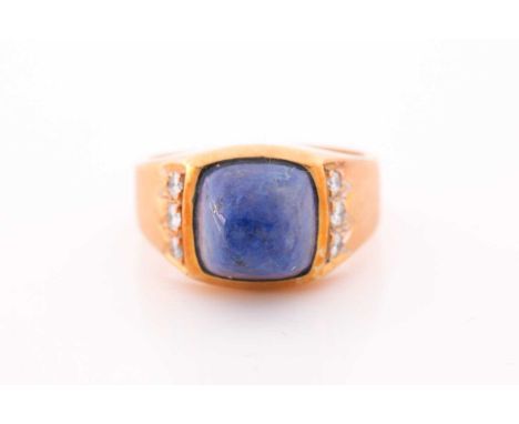 A yellow metal, lapis lazuli and diamond dress ring, set with a domed lapis with smoothed sides, the shoulders inset with sma