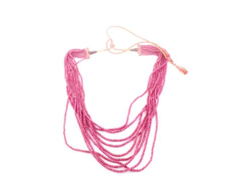 An Indian ruby beaded necklace, set with nine strands of graduated rounded ruby beads, fastened with red and gilt ties.