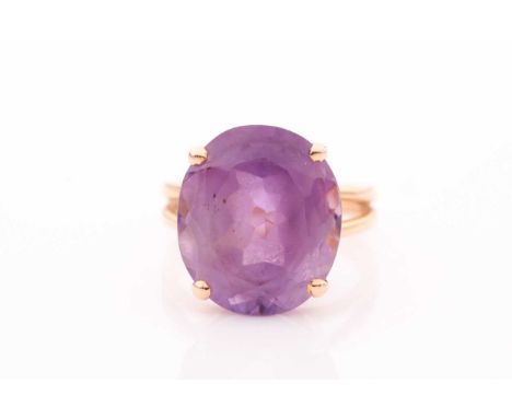 A single stone amethyst dress ring, the deep oval cut stone in four claw mount, to an unmarked bifurcated shank. Ring size L 