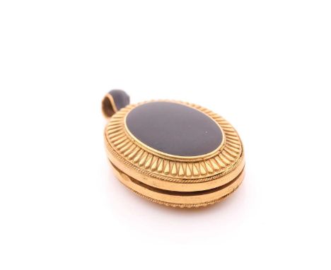 A Victorian gilt metal and black enamel locket, the case with a plain black enamel oval to centre, with lobed decoration to b