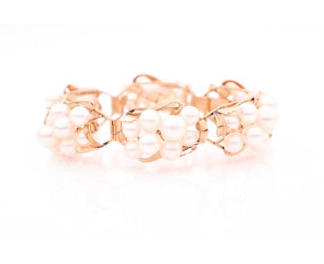 A yellow metal and pearl bracelet, each segment cluster set with rounded pearls of various sizes, fastened with a safety chai