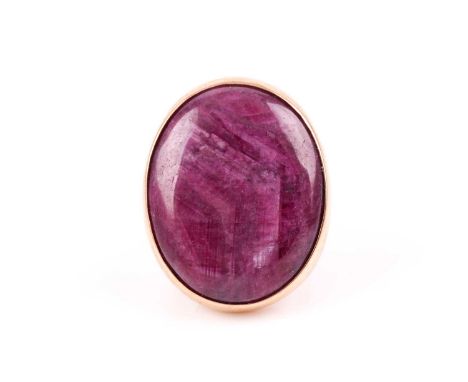 A 9ct yellow gold and ruby ring, set with a large oval cabochon corundum segment, 3 x 2.5 cm, rubover set, the yellow gold sh