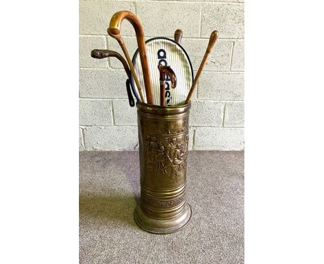 A brass embossed walking stick stand, together with associated canes, including a gnarled wood vintage cane with leather stra