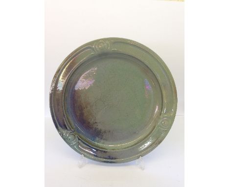 A Carter & Co. Poole Pottery green lustre charger, designed and modelled in relief in the Arts & Crafts style by James Radley