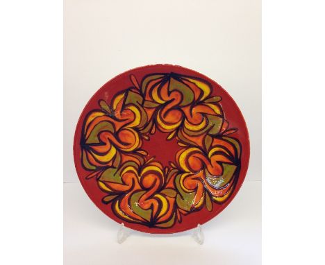 A Poole Pottery Delphis charger, shape 54, decorated in an abstract pattern in tones of orange, yellow and green by Lynn Greg