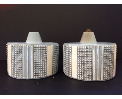 A pair of mid 20th century Poole Pottery Robert Jefferson design carved circular lamp bases, decorated in tones of grey and w