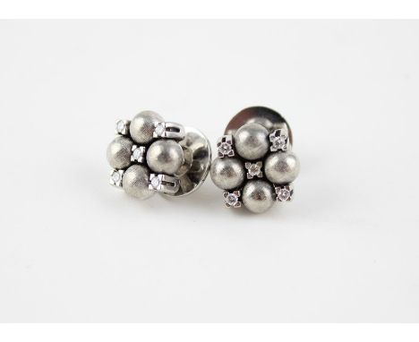 A pair of white metal and diamond earrings, having eight arm square form mount, four with finely engine turned spheres altern