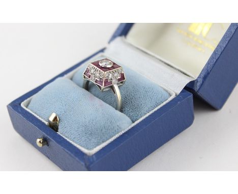 A white metal, diamond and ruby dress ring, having raised square mount with tapering sides, the face with round cut diamond i