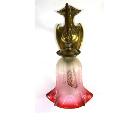 An Art Nouveau brass bracket light fitting with cranberry glass shade.