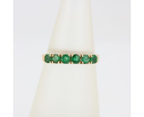 A 14ct yellow gold emerald set half eternity ring, (M).