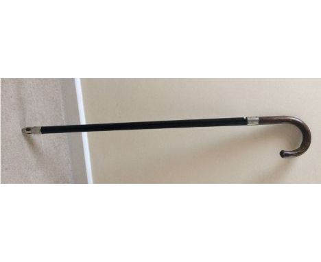 This Bekko Novelty Walking Stick has a grained wood handle and a hard black bakelite  shaft. A “silver” band is mounted at th