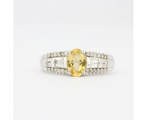 A 9ct white gold ring set with an oval cut yellow topaz and diamonds, (O).