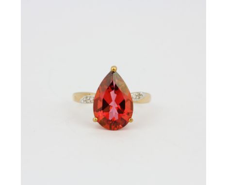 A 9ct yellow gold ring set with a large pear cut red stone and diamonds, (M).