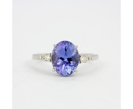 An 18ct white gold ring set with an oval cut tanzanite and diamonds, (O).