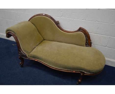A VICTORIAN MAHOGANY GREEN UPHOLSTERED CHAISE LONGUE with floral carving to frame and scrolled end on shaped legs terminated 