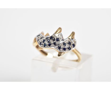 A 9CT GOLD SAPPHIRE AND DIAMOND RING, in the form of two over lapping dolphins, set with circular cut sapphire bodies and sin