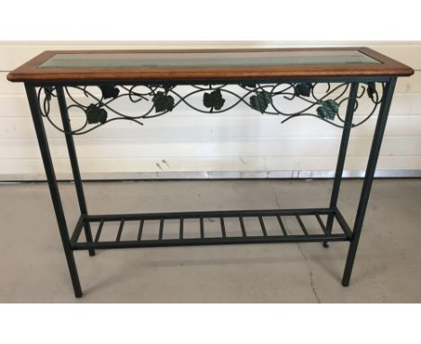 A modern wrought iron hall table with wooden top and bevel edged glass insert. Base painted green with scroll and leaf design